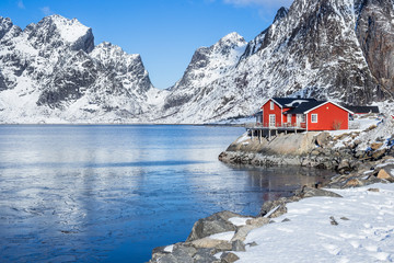 Red fisherman´s house on Lofoten islands in front of a fjord at a beautiful sunny winter day - obrazy, fototapety, plakaty
