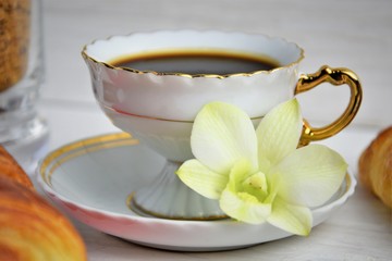 Stilllife of coffee cup with espresso, croissants, biscuits, tender flower, brown sugar on a wooden background