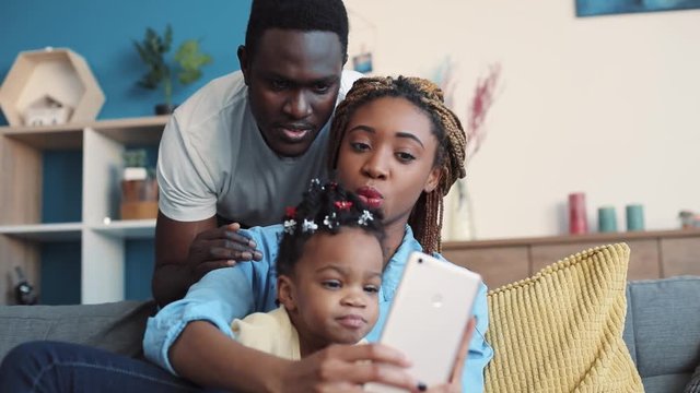 Cheerful African American family takes selfie in their cozy living room. Having fun, social networks, modern culture. Slow motion, close up view