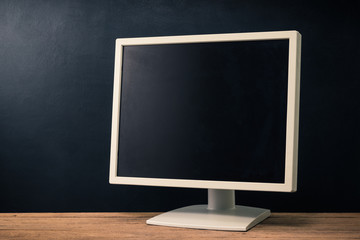 old and obsolete computer monitor on old wood table against rough and dark background