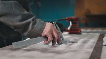 Worker making measurements and marks on the metal part using a caliper