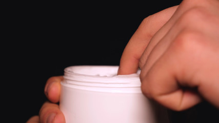 Cream for hands (face), in a white jar, on a black background.