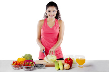 African girl preparing healthy salad on studio