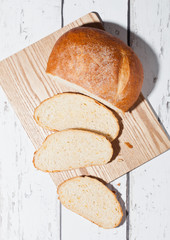 Freshly baked bread loaf with pieces on wood board