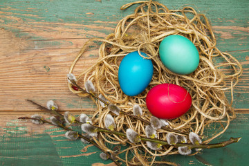 Easter background with eggs, nest and catkins on old wooden background. Copy space