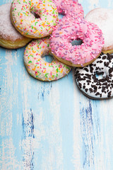 Traditional donuts on white wooden background.  Tasty doughnuts with icing and powdered sugar, copy space