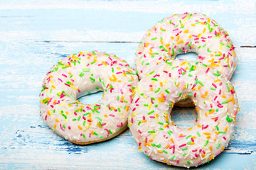 Traditional donuts on blue wooden background. Tasty doughnuts with icing, copy space