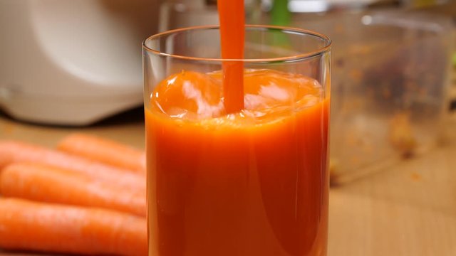 Pouring fresh squezzed carrot juice iinto glass. Healthy food, natural source of vitamin a. Slow motion