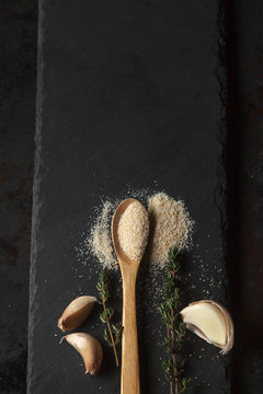 Garlic powder and cloves on black slate board