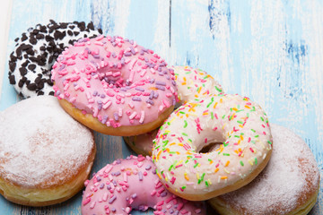 Traditional donuts on white wooden background.  Tasty doughnuts with icing and powdered sugar, copy space