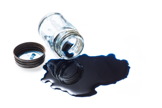 Deep blue colour ink spill from old glass inkwell with the rusty cap on white background