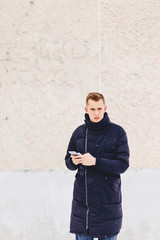 Fototapeta na wymiar guy in winter jacket writes sms