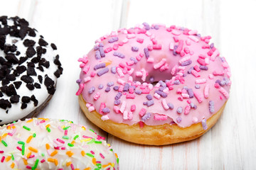 Traditional donuts on white wooden background.  Tasty doughnuts with icing, copy space