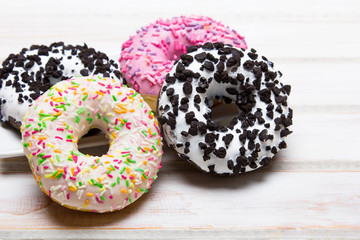 Traditional donuts on white wooden background.  Tasty doughnuts with icing, copy space
