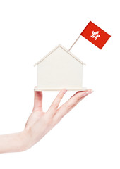 Fototapeta na wymiar Female hand holding wooden house model with flag