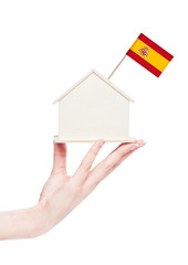 Naklejka premium Female hand holding wooden house model with flag