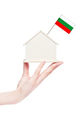Fototapeta na wymiar Female hand holding wooden house model with flag