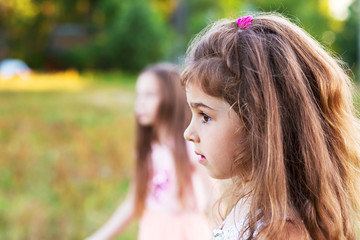 Beautiful little girl with long curly hair, looking worried at summer day.  Place for text