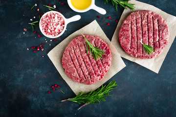 Fresh minced beef meat burgers with spices on dark background. Raw ground beef meat. Flat lay. Top...