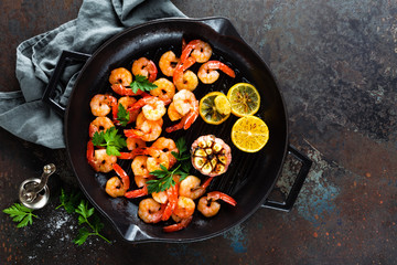Prawns roasted on grill frying pan with lemon and garlic. Grilled shrimps, prawns. Seafood. Top view. Dark background
