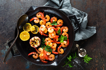 Prawns roasted on grill frying pan with lemon and garlic. Grilled shrimps, prawns. Seafood. Top view. Dark background