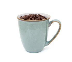 Green mug filled with dark roasted coffee beans
