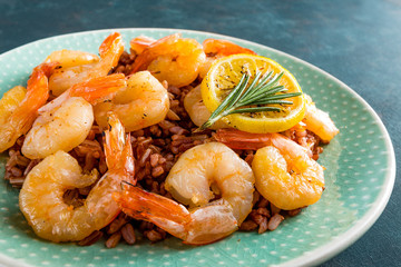 Prawns roasted on grill and boiled brown rice on plate. Grilled shrimps, prawns with rice. Seafood. Asian cuisine. Closeup. Dark background