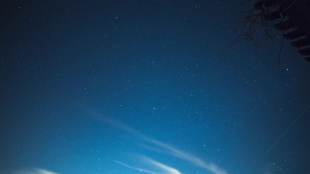 Time lapse of night sky with stars and light clouds.