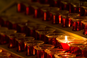 Close-up of warm lighting candle on holder in dark temple