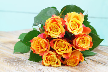 Orange roses bouquet covered in glitter on wooden surface with copy space
