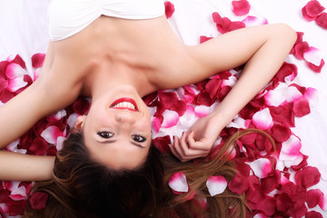 Obraz na płótnie Canvas Beautiful girl in petals of roses