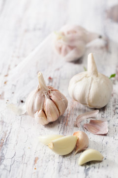 Peeled cloves of garlic and a head of garlic on old wooden table