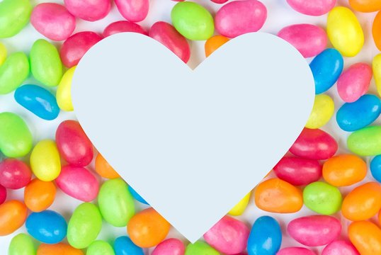 Colorful jelly bean background with white heart shaped space for