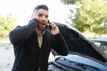 angry man calling by phone with damaged car