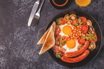 Traditional full English breakfast with fried eggs, sausages, beans, mushrooms, grilled tomatoes and bacon.