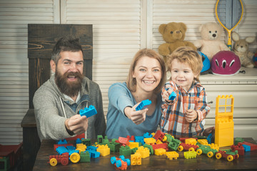 Naklejka premium Young family play game with construction plastic blocks.