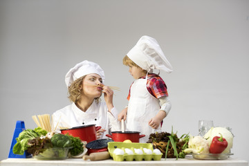 Mom and kid with smiling face play with spaghetti together.