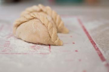 Homemade dumplings with flour laying on the modern cooking surface.