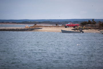 Fototapeta na wymiar Red pickup on a coast with a boat