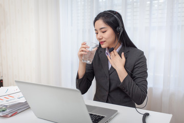 Call center operator. Drinking water while working with laptop computer