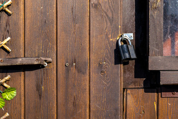 metal door lock on a brown background dark wooden door with glass and plant closeup