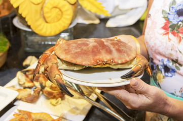 Big red crab on a plate in the hands of a girl