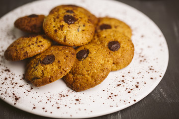 Chocolate cookies placed on a plate on a dark background.