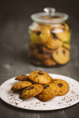 Chocolate cookies placed on a plate on a dark background.
