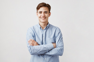 Portrait of handsome young man in casual blue shirt. Boy smiles for the camera expressing happiness...