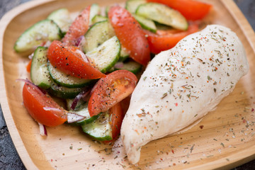 Bamboo tray with boiled chicken breast and vegetable salad, close-up, selective focus