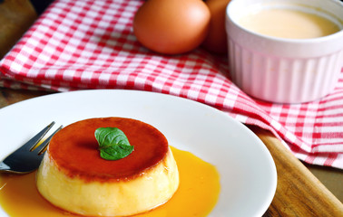 Caramel custard desert on white dish with wooden background
