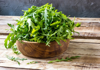 Fresh arugula leaves on wooden bowl