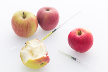 Apple with punched needles and syringes as a concept for modifying food / white background