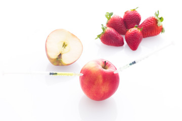 Modified food, fruits,apple and strawberries with punched needles and syringes / isolatet on a white background